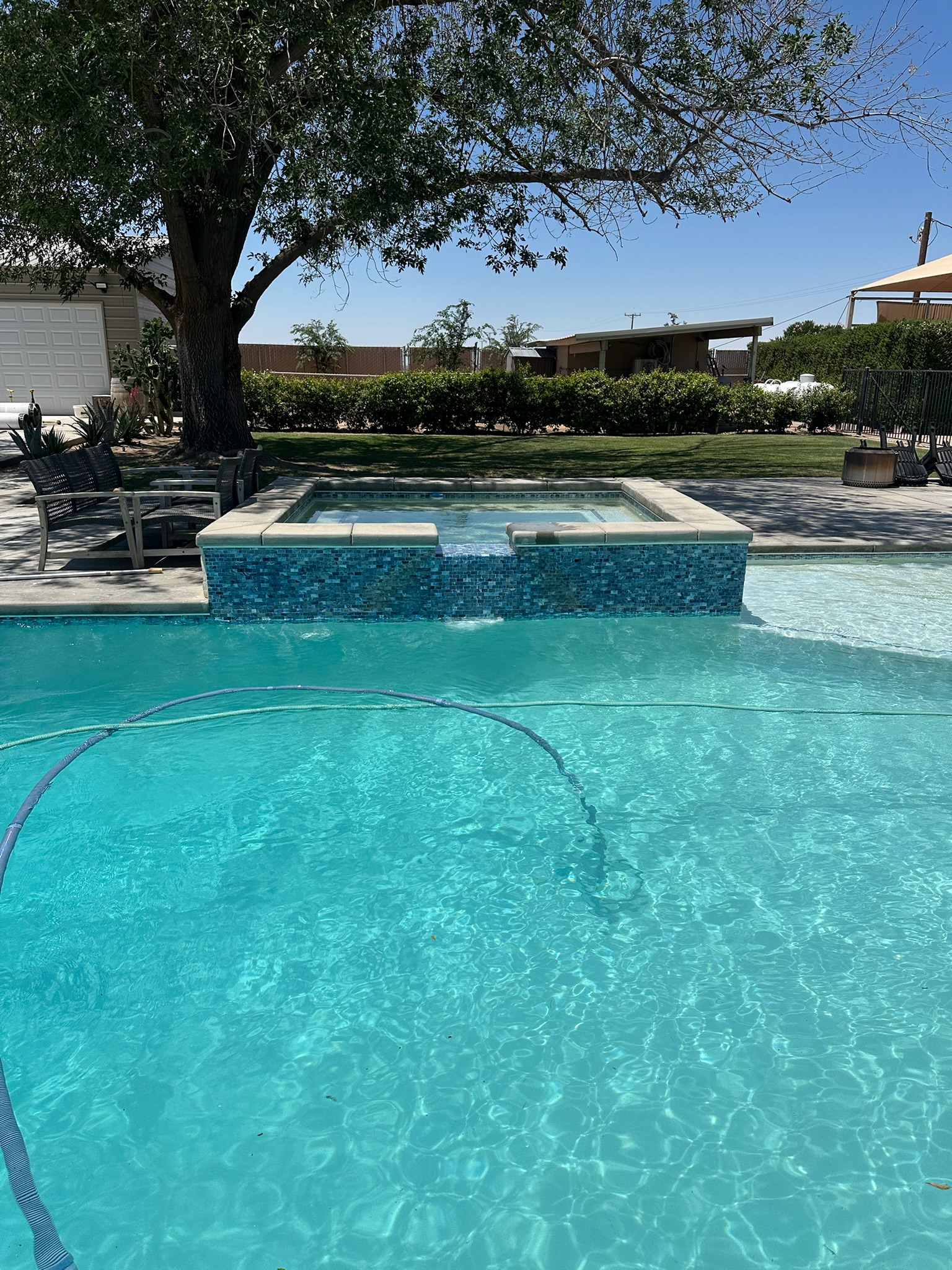 Pool and raised spa in a shaded backyard